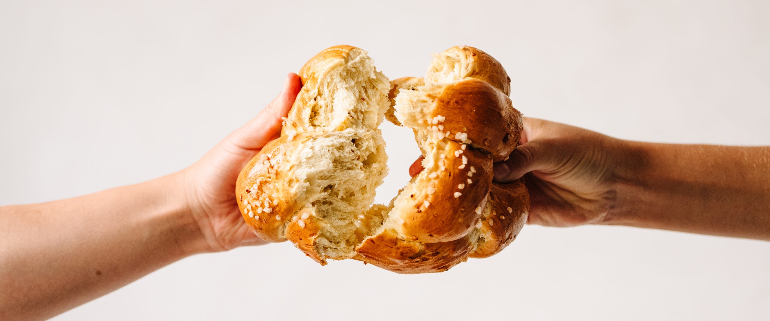 Scheffel Hefezopf von zwei Seiten gegriffen und wird in der Mitte zerbrochen.